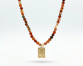 Necklace with multicolored beads and a gold pendant on a white background