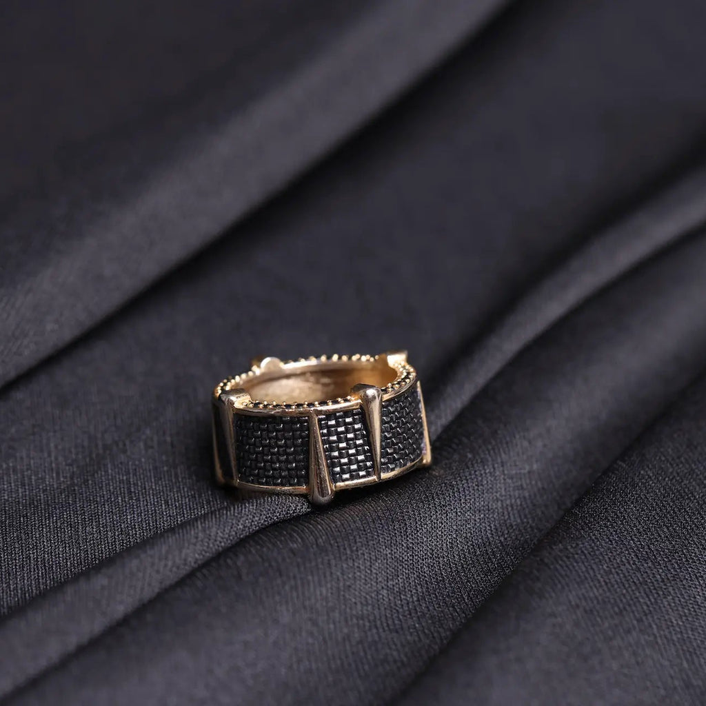 Gold ring with black gemstones on a dark fabric background